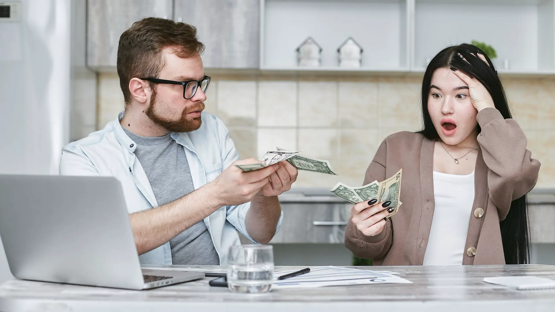 A man hands over cash while a woman looks shocked at how little money is left