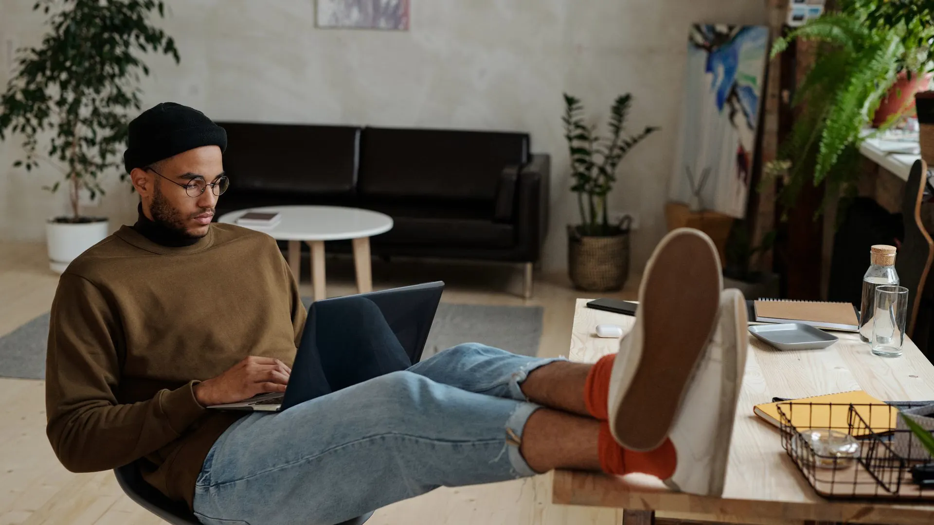 A freelancer works on a laptop with feet up on the desk in a home office